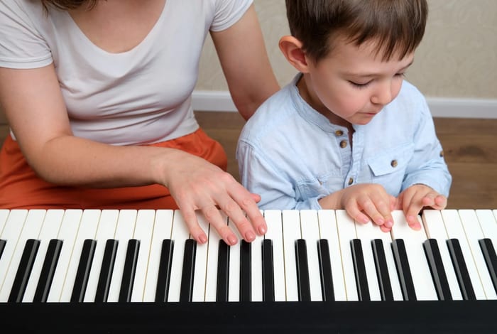 Parent and child practising piano together at home