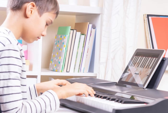 Tablet on stand beside keyboard for online piano lesson setup