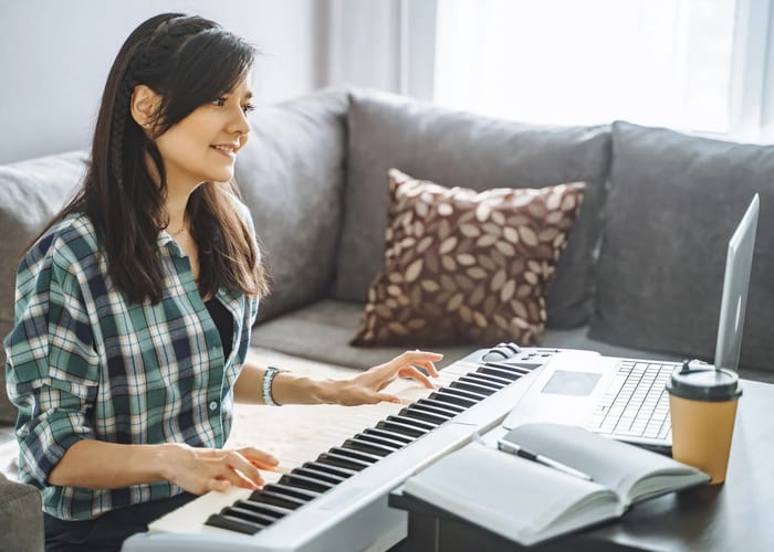 Home music setup with keyboard and laptop for online piano lessons